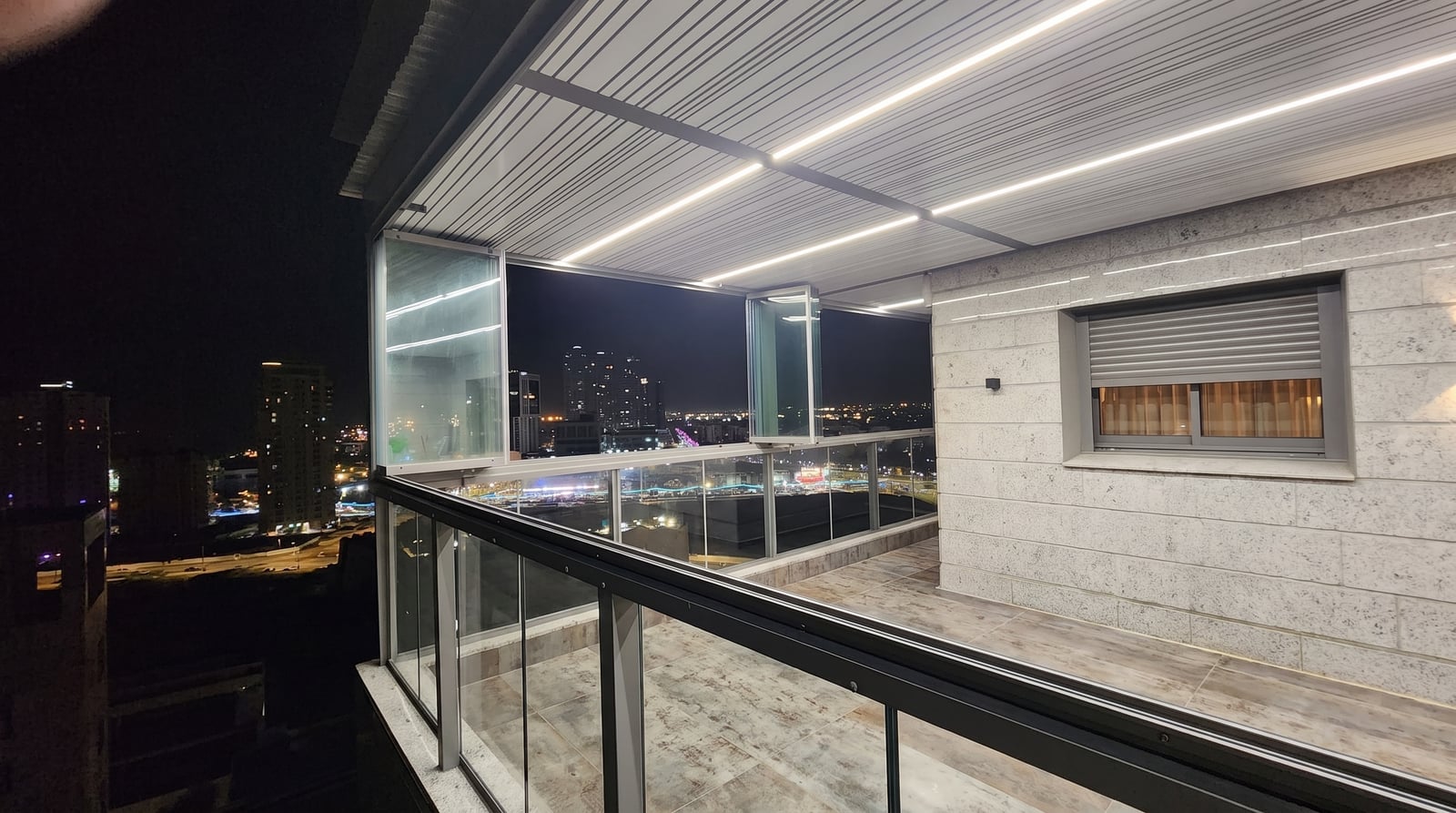 מרפסת בלילה עם סגירת זכוכית עליונה פתוחה בחלקה ותקרה מוארת בלד