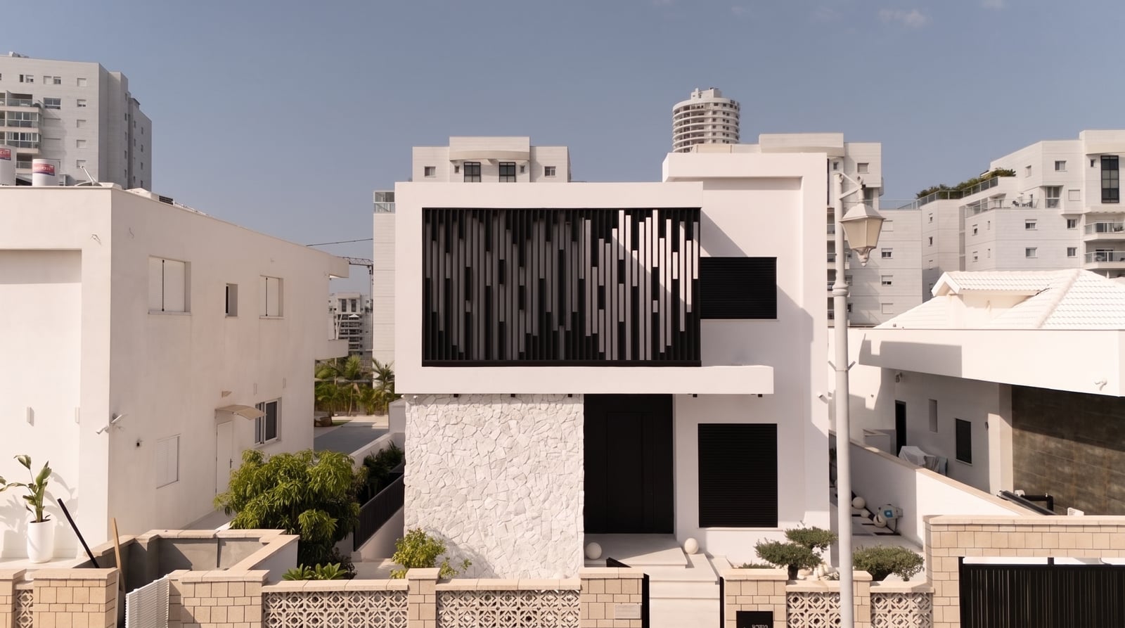 קומה עליונה של בית לבן עם לוברים אנכיים שחורים בדוגמה משתנה