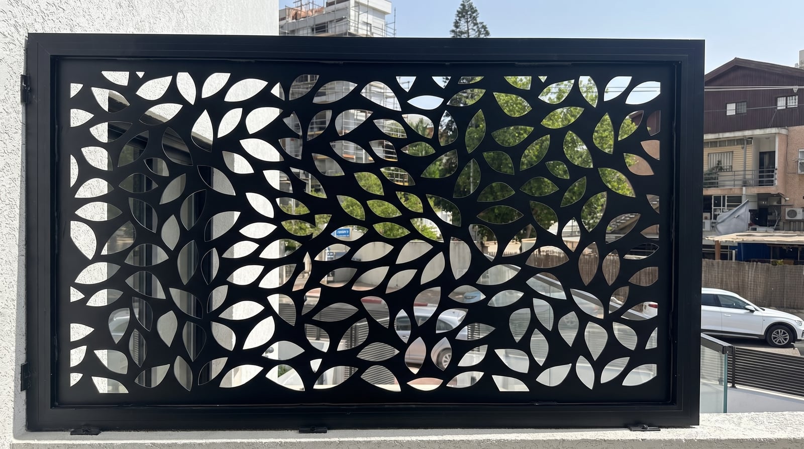 פאנל משרביה שחור בדוגמת עלים על מעקה מרפסת, מבט אל הרחוב