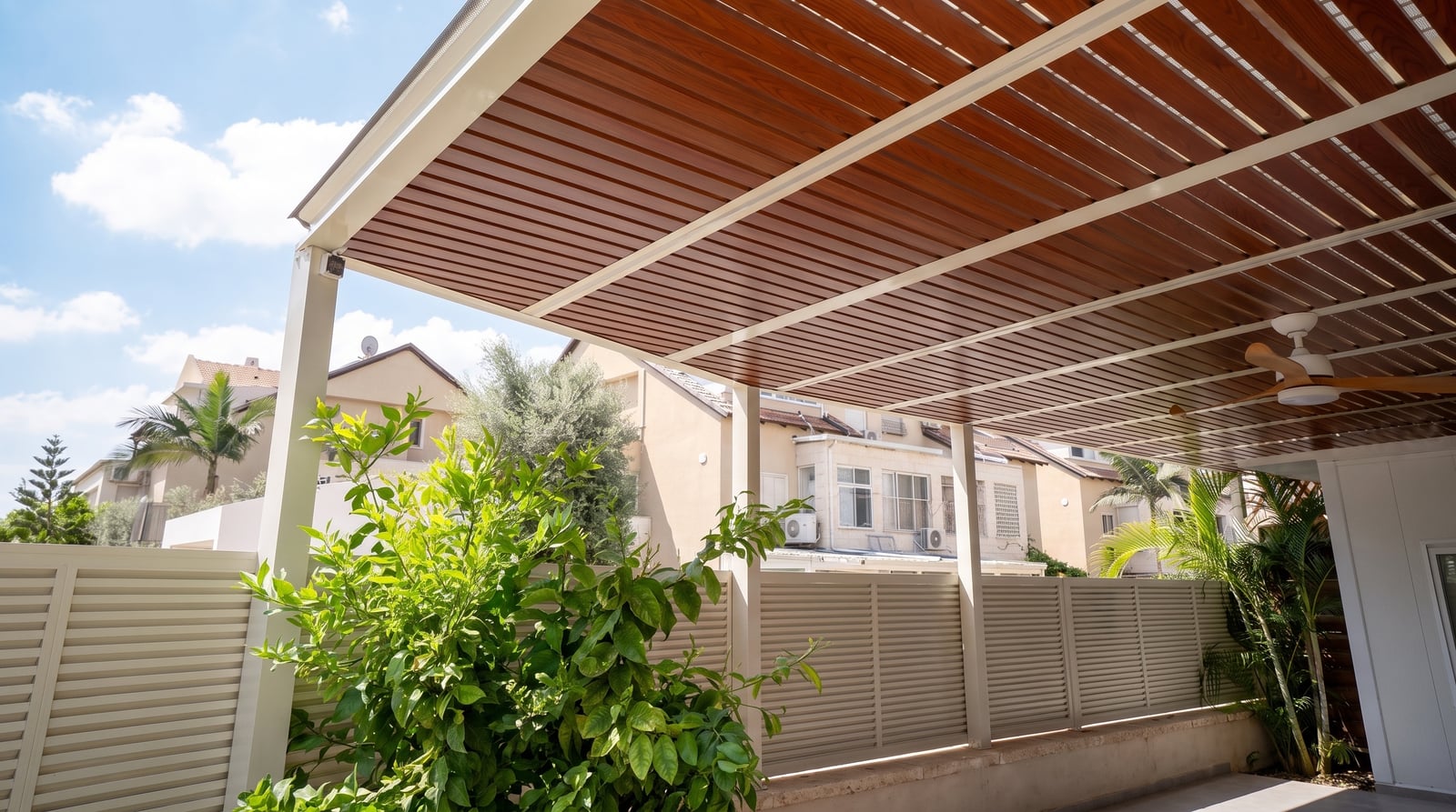 פרגולה עם מסגרת קרם ושלבים בגוון עץ, מאוורר תקרה וגדר לוברים בהירה