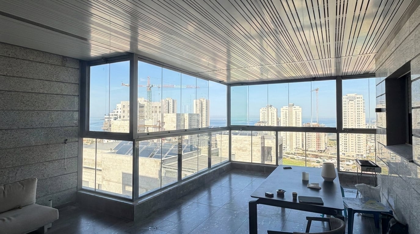 מרפסת עם סגירת זכוכית ותקרת שלבים בהירה, נוף לבניינים ולים