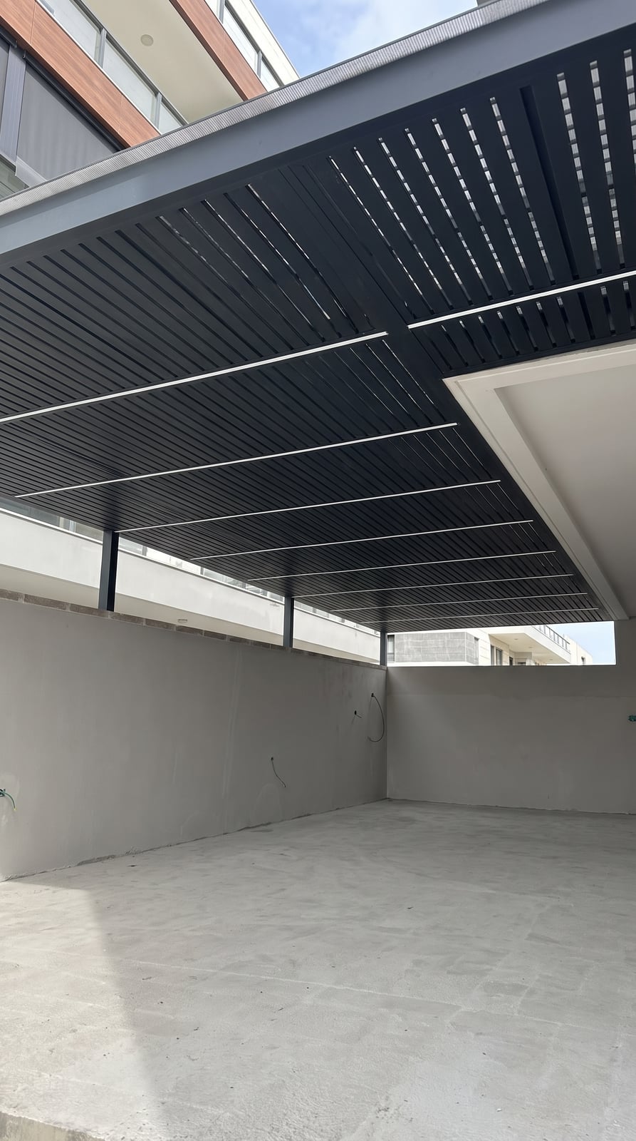 פרגולת אלומיניום שחורה עם פסי לד מעל מרפסת בשלב בנייה