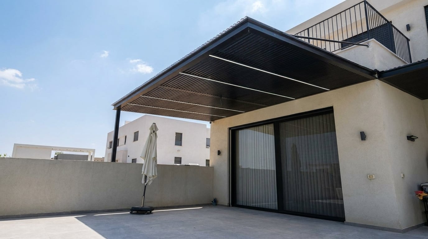 פרגולה שחורה עם פסי לד מעל מרפסת מרוצפת ליד דלת הזזה